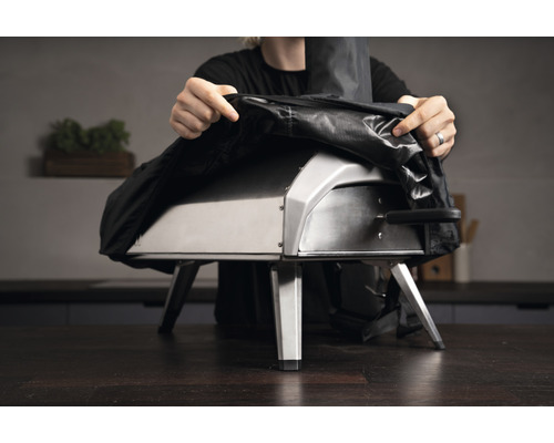 Person legt eine Abdeckung auf einen Pizzaofen.