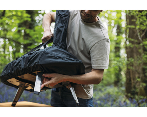 Mann verstaut Pizzaofen in einer Tragetasche im Freien