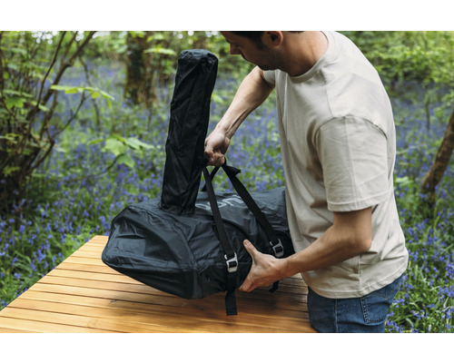 Mann packt verpacktes Campingbett auf einen Tisch