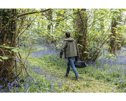 Mann mit Tasche geht durch einen Wald mit blühenden Hyazinthen