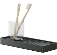 Zwei Zahnbürsten in einem Glas auf einer schwarzen Ablage für das Badezimmer