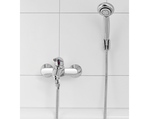 Ensemble de douche avec robinetterie murale devant un fond de carreaux blancs