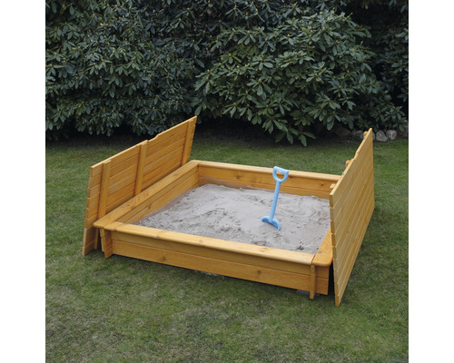 Sandkasten aus Holz mit Sand und Schaufel im Garten