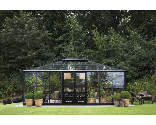 Serre avec table, chaises et plantes dans le jardin.
