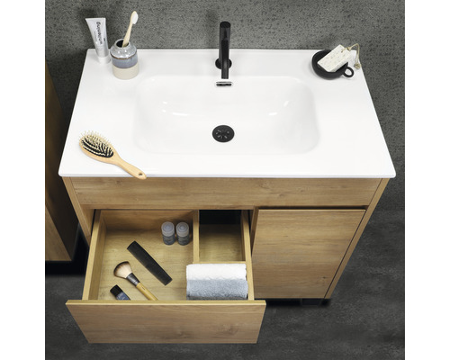 Meuble sous-lavabo en bois avec tiroir ouvert et divers articles de salle de bains sur le dessus