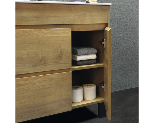 Meuble de salle de bain avec porte ouverte, serviettes et papier toilette
