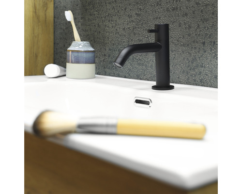 Lavabo de salle de bain avec robinet, brosse à dents, gobelet et pinceau de maquillage