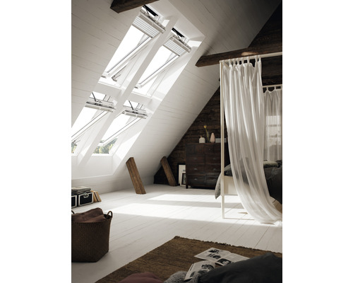 Chambre mansardée lumineuse avec fenêtres de toit et mobilier de chambre