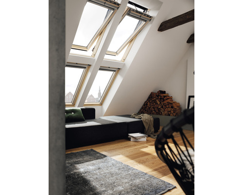 Helles Dachzimmer mit Dachfenstern, Sofa und Holzlager