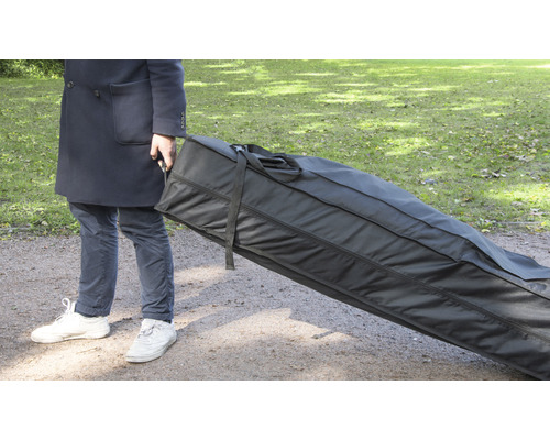 Une personne transporte un grand sac de transport noir à l''extérieur.