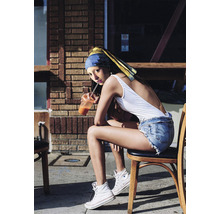 Une jeune femme portant un foulard est assise sur une chaise avec une boisson.