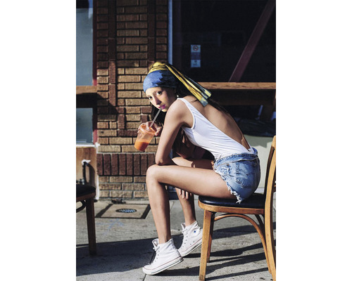 Une jeune femme portant un foulard est assise sur une chaise avec une boisson.