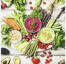 Gemüseplatte mit Dips, Karotten, grünen Bohnen, Radieschen, Spargel, Zucchini, Tomaten und Avocado auf einem Tisch