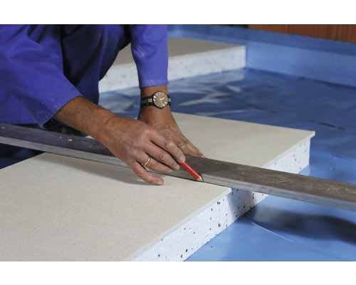 Handwerker markiert Dämmplatte mit Bleistift und Richtscheit