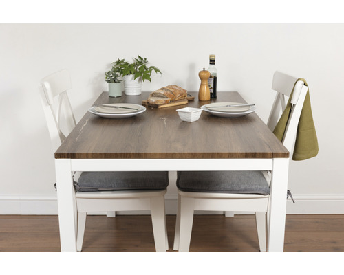 Table de salle à manger avec deux chaises, vaisselle, pain, moulin à épices et burette à huile sur un plateau de table