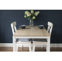 Esstisch mit Holztischplatte, weißen Stühlen und Dekorationsschalen