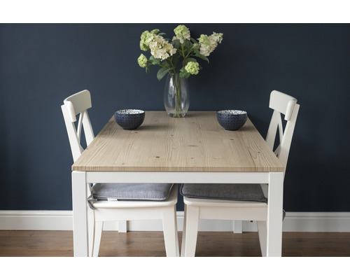 Esstisch mit Holztischplatte, weißen Stühlen und Dekorationsschalen