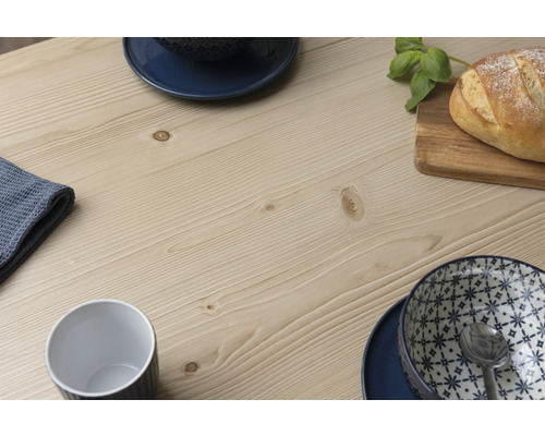 Detailansicht einer Tischplatte aus Holz mit Geschirr und Brot