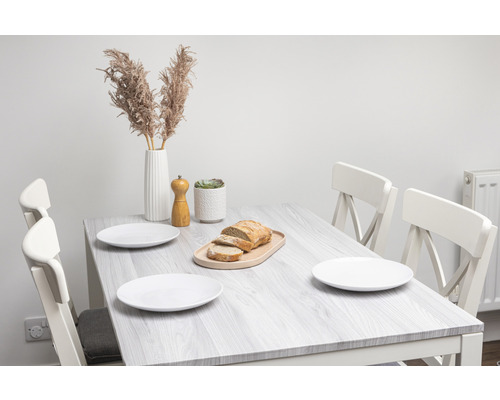 Esstisch mit Stühlen, Tellern, Brot, Pfeffermühle und Dekoration