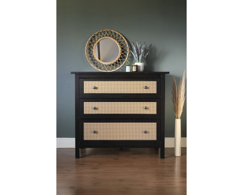 Commode à trois tiroirs en bois et en rotin tressé devant un mur avec miroir et décoration.