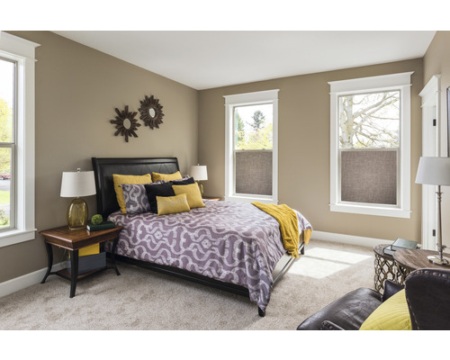 Schlafzimmer mit Bett, Nachttischen und Fenstern mit Textilrollos