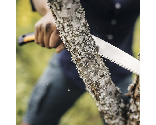 Une personne scie un tronc d''arbre avec une scie à main.