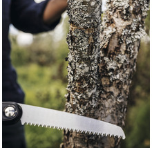 Gros plan d''une scie à main coupant une branche