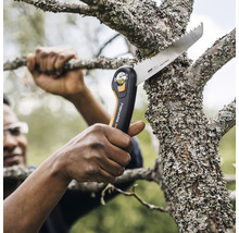 Une personne coupe une branche avec une scie à main.