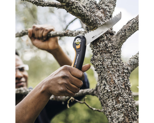 Une personne coupe une branche avec une scie à main.