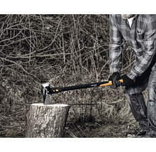Person spaltet Holz mit einer Fiskars Spaltaxt auf einem Holzscheit