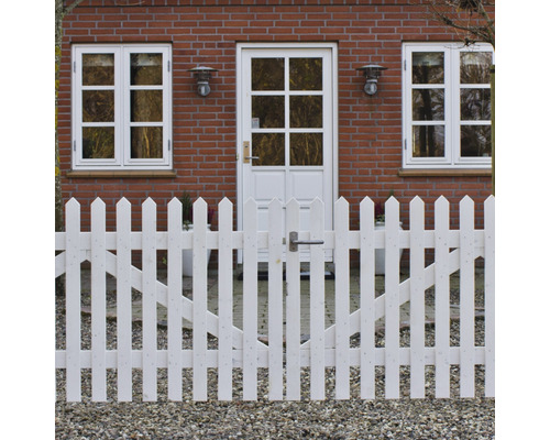 Weißer Holzzaun mit Gartentor vor einem Backsteinhaus