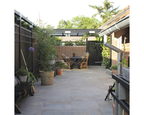Espace extérieur aménagé avec terrasse, clôture de jardin, plantes et coin salon