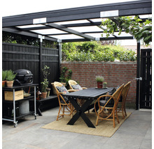 Terrasse couverte avec table à manger, chaises en rotin, chariot de barbecue et clôture