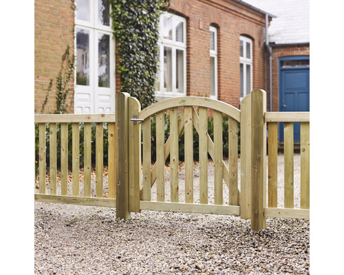 Holzzaun mit Tor vor Backsteinhaus