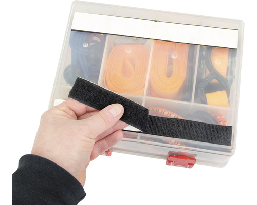 Une personne tient une fermeture velcro devant une boîte d''assortiment avec des sangles d''arrimage.
