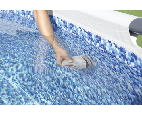 Une main tient un accessoire de nettoyage de piscine dans l''eau d''une piscine.