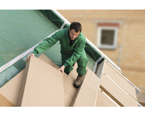 Un homme pose des panneaux isolants sur un toit.