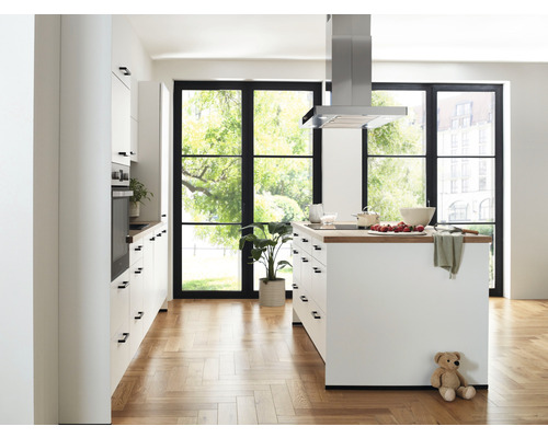 Cuisine claire avec îlot de cuisine, hotte aspirante et grandes fenêtres pour beaucoup de lumière naturelle