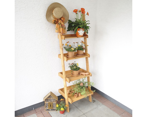 Holz Pflanzenregal mit vier Ebenen, Blumen, Strohhut und Insektenhotel vor einer Wand