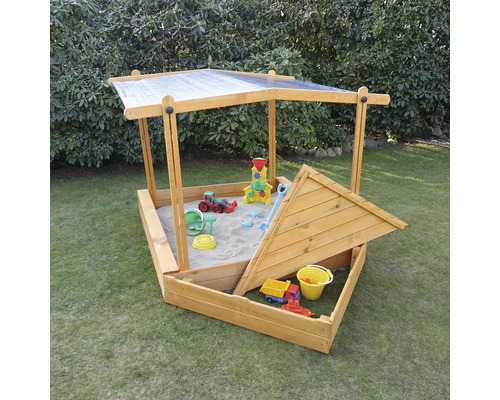 Bac à sable en bois avec toit et jouets de sable dans le jardin
