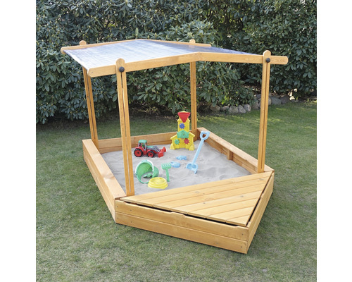 Bac à sable avec toit et jouets de sable dans le jardin