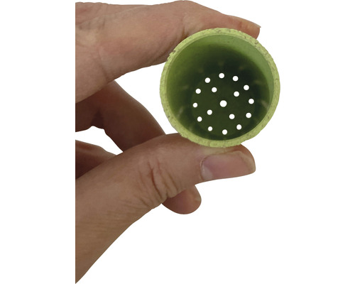 Un couvercle de drain vert est tenu par une main.