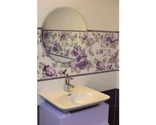 Salle de bains avec lavabo, robinet et miroir devant des carreaux muraux à motifs floraux