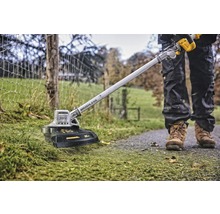 Vue de dessus d''une personne coupant la pelouse avec une débroussailleuse à batterie