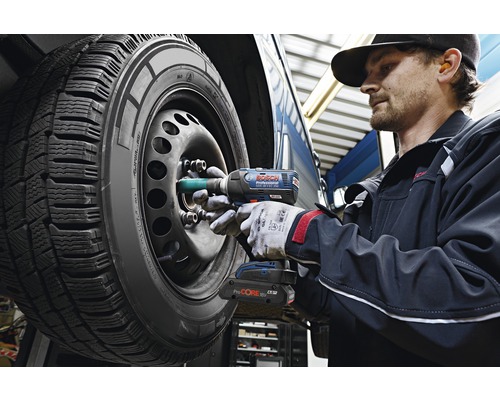 Un mécanicien utilise une clé à chocs sans fil pour serrer les écrous de roue d'un pneu de voiture