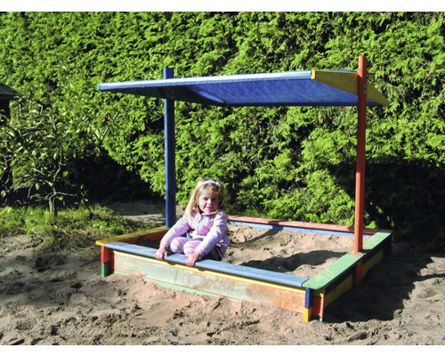 Enfant dans un bac à sable avec protection solaire dans le jardin
