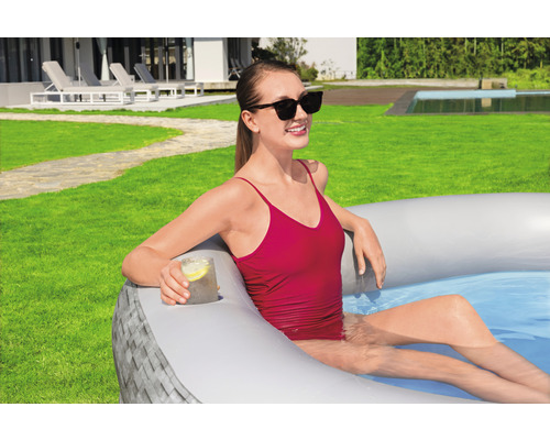 Frau entspannt in einem aufblasbaren Pool im Garten mit Getränkehalter.