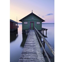 Holzsteg führt zu einem Haus auf Stelzen im Wasser.