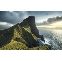 Landschaft mit einem Leuchtturm auf einer grünen Klippe am Meer unter bewölktem Himmel.
