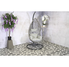 Scène avec un fauteuil suspendu en rotin, une glycine artificielle et une orchidée suspendue.